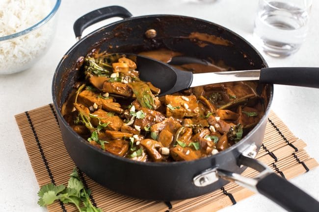 Tofu satay curry in a frying pan with a big spoon