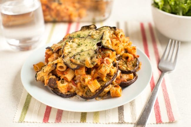 Portion of cheesy eggplant parmesan pasta bake on a plate with a fork