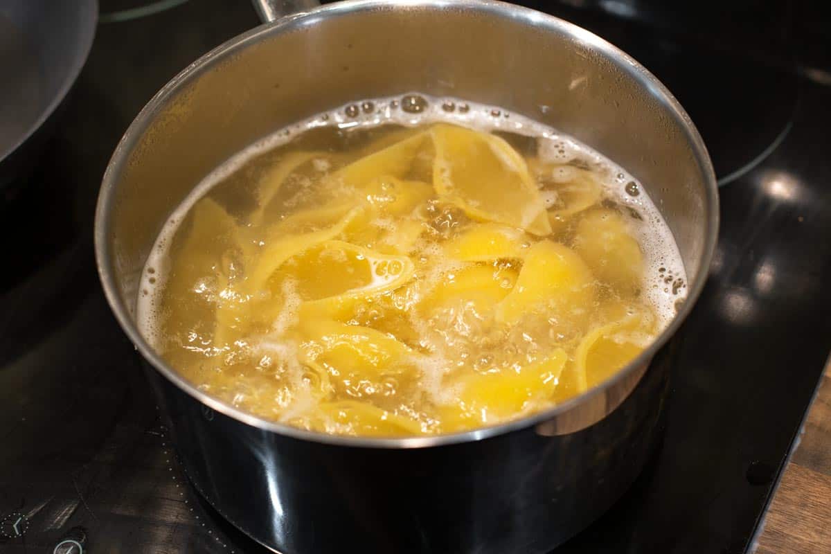 Large pasta shells boiling in a saucepan.