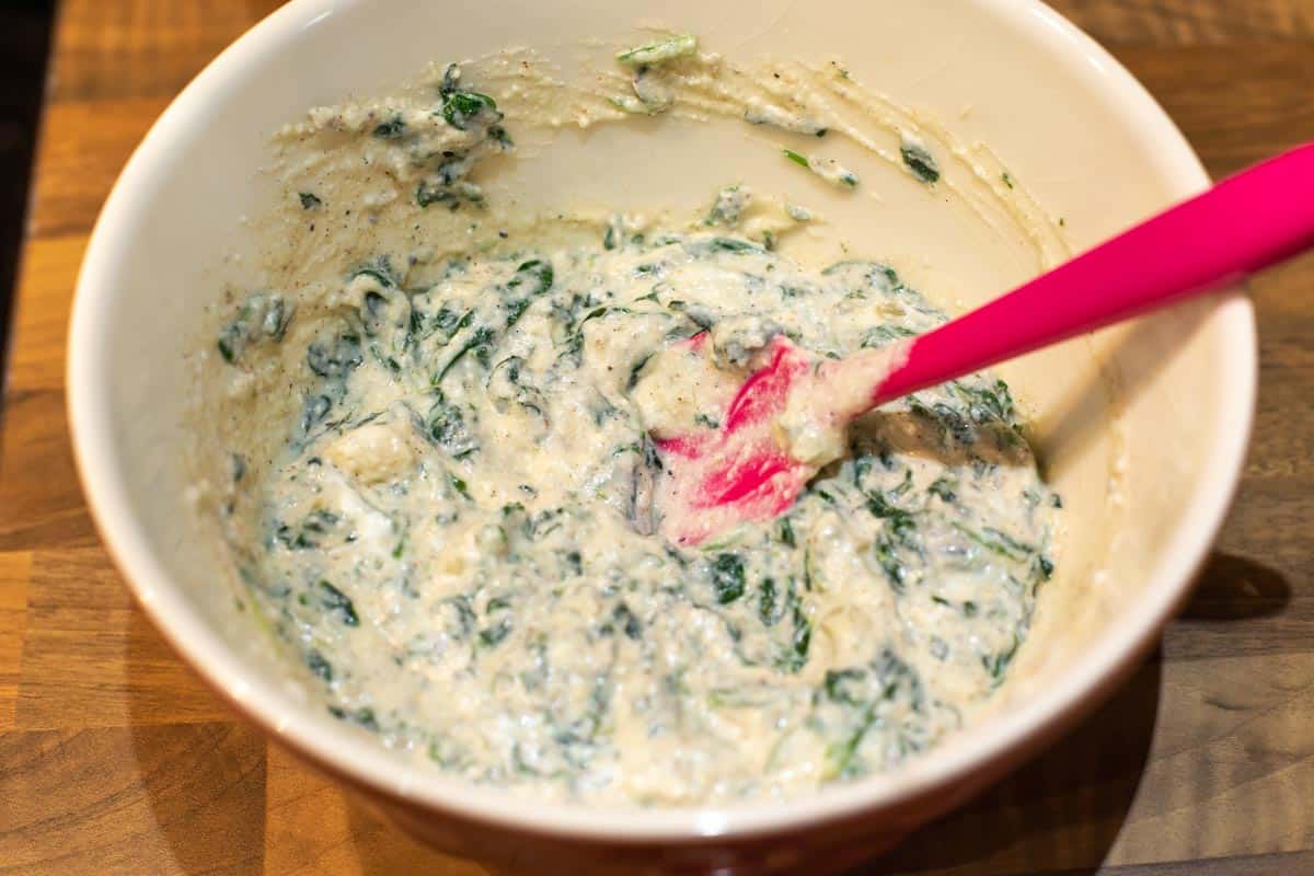 A creamy spinach and ricotta mixture in a mixing bowl.