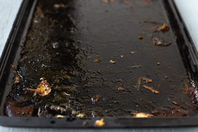 A baking tray that needs deglazing, covered in scraps of roasted vegetables and caramelised honey.