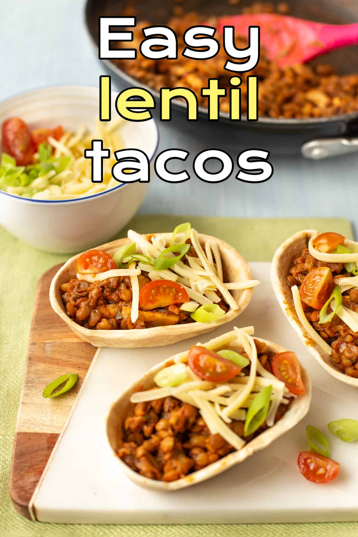 Vegetarian lentil tacos topped with cheese and cherry tomatoes.