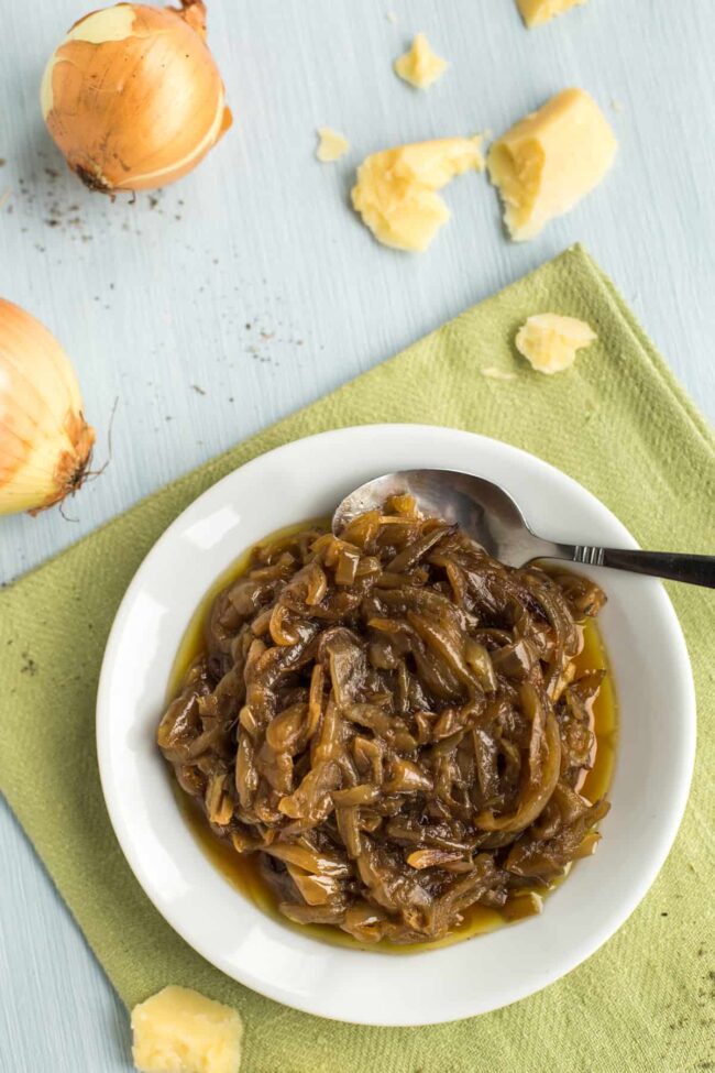 A plateful of caramelised onions surrounded by raw onions and chunks of cheddar cheese.