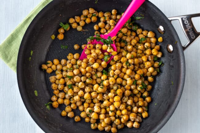 Herby chickpeas cooking in a frying pan.