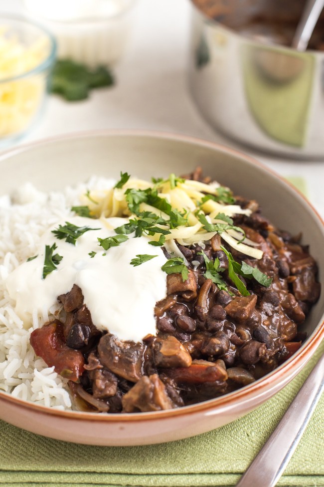 Mushroom and black bean chilli in a bowl with rice, cheese and sour cream