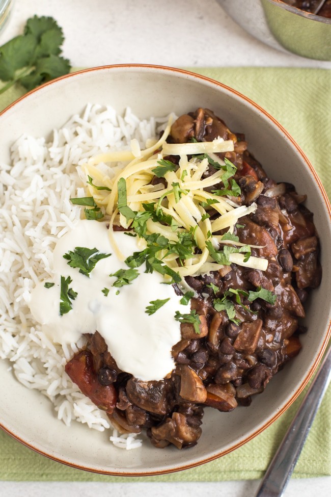 Mushroom and black bean chilli in a bowl with rice, cheese and sour cream