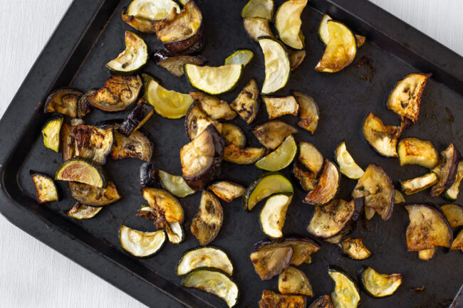 Roasted aubergine and courgette on a baking tray.