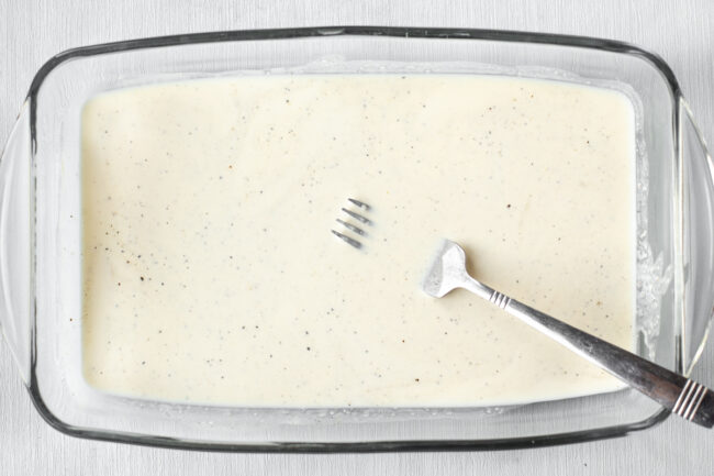 Cream sauce in a baking dish with a fork.