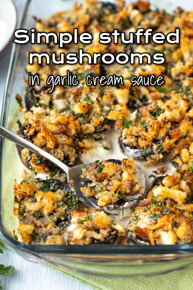 A dish full of stuffed mushrooms in a cream sauce, with a spoon taking a scoop.