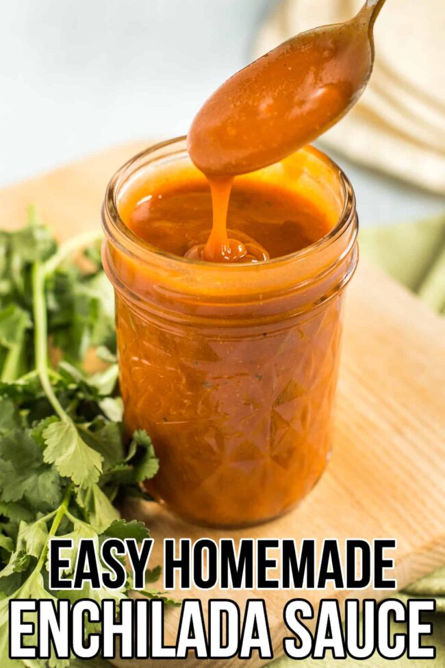 Jar of homemade enchilada sauce with a spoon lifting up a spoonful.