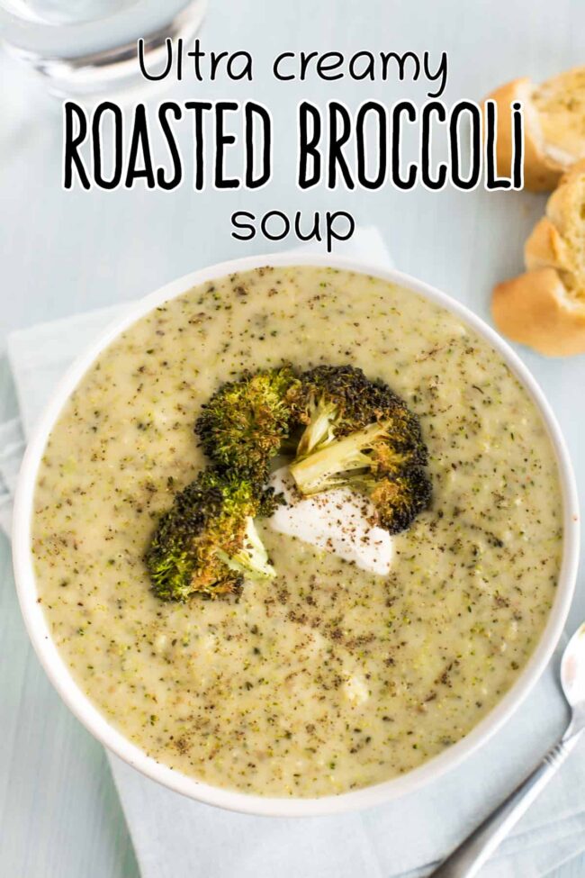 A bowlful of cheesy broccoli soup topped with roasted broccoli and sour cream.
