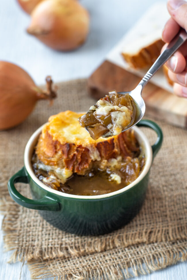 A spoon taking a scoop of French onion soup.