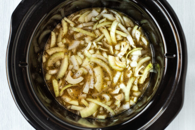 Raw sliced onions in a slow cooker.