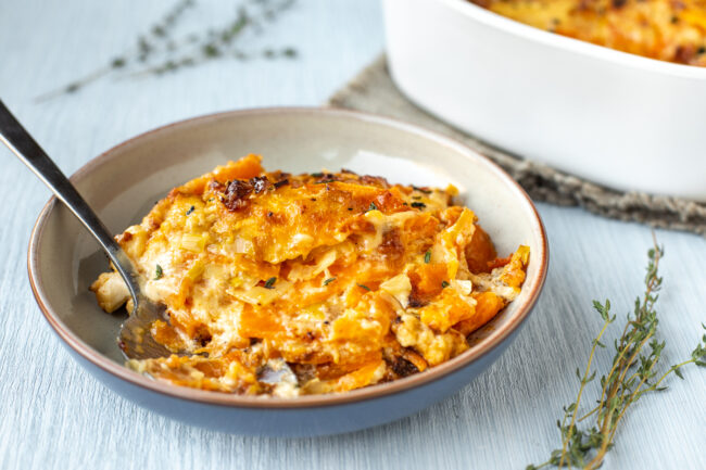 A bowlful of creamy sweet potato gratin with buttered leeks and a crispy topping.