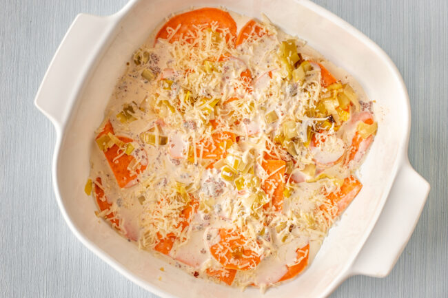 Sweet potato with cream and leeks in a baking dish.