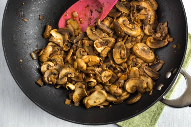 Garlic mushrooms cooking in a wok with smoked paprika