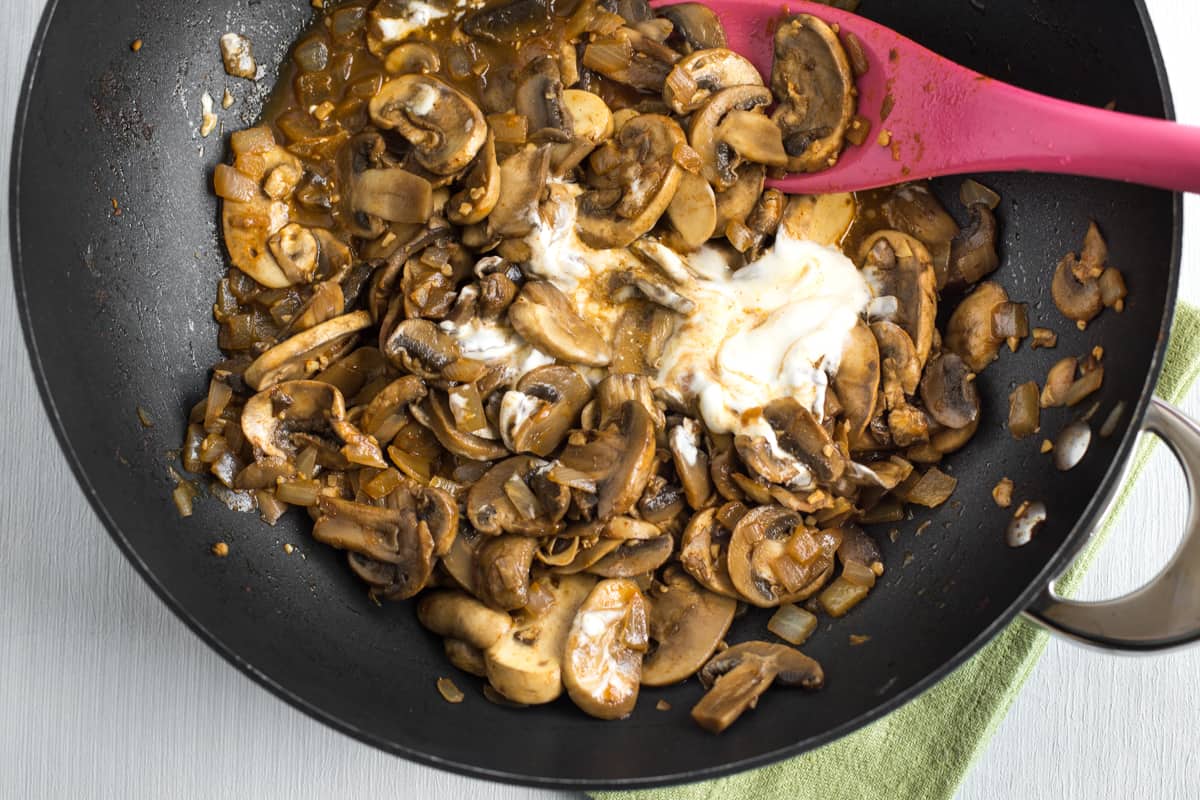 Smoky garlic mushrooms in a wok with a dollop of sour cream added