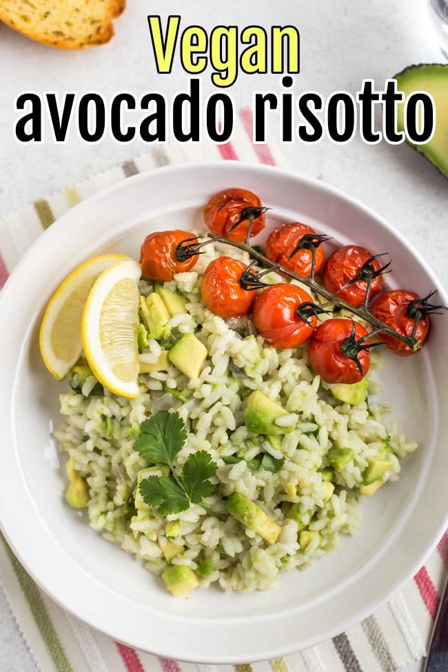 Portion of avocado risotto in a bowl with lemon wedges and roasted tomatoes