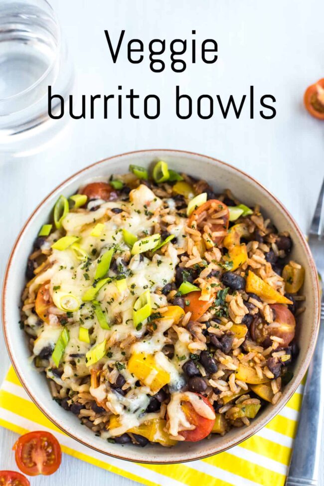 A veggie burrito bowl topped with melted cheese and spring onions.