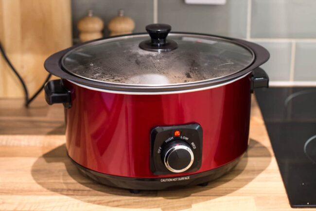 A large red slow cooker on a kitchen counter.