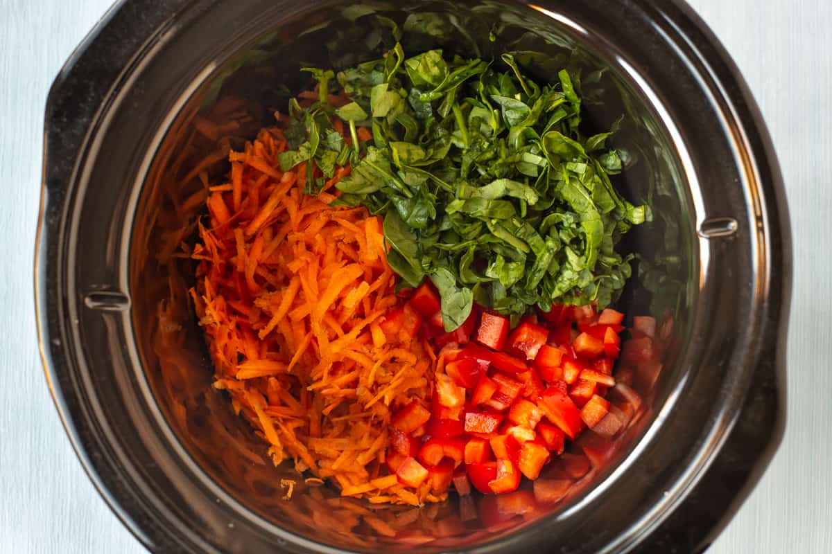 Grated carrot, spinach and red pepper in a slow cooker.