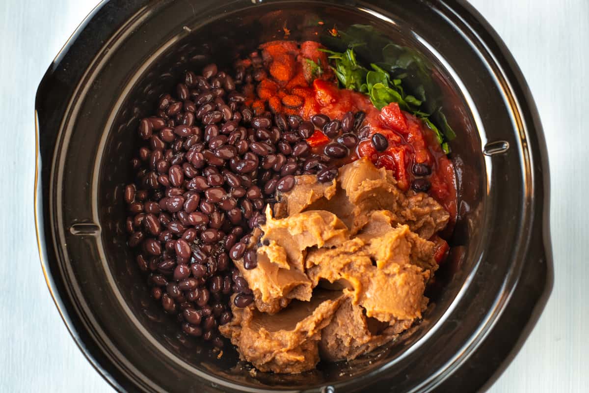 Black beans, chopped tomatoes and refried beans in a slow cooker.