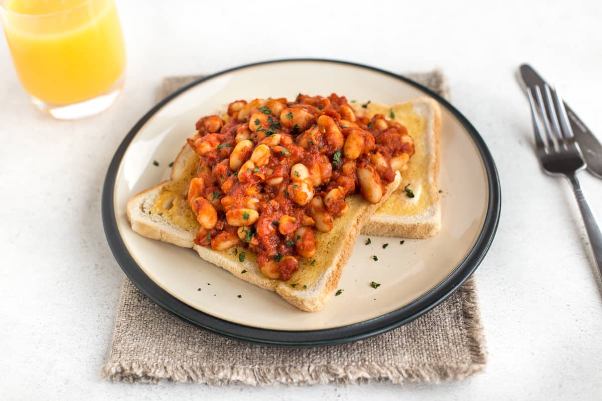 Homemade vegetarian baked beans on buttered toast topped with parsley.