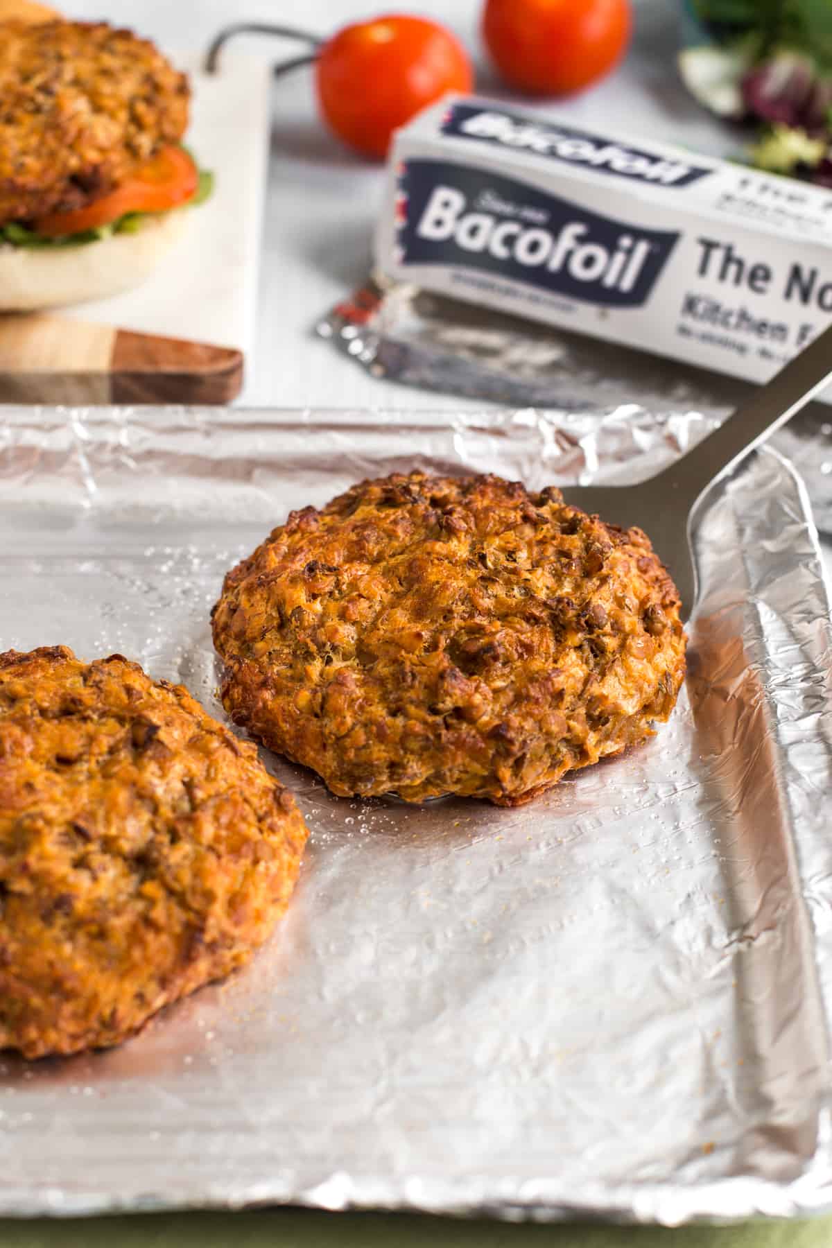 Cheesy lentil burger on a foil-lined baking tray.