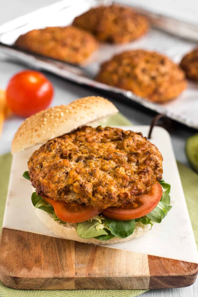 Cheesy lentil burger placed inside an open bun with tomato and lettuce.