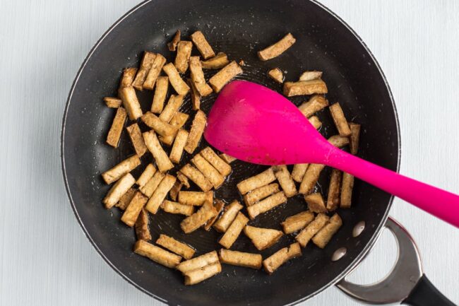 Smoked tofu being cooked in a frying pan.