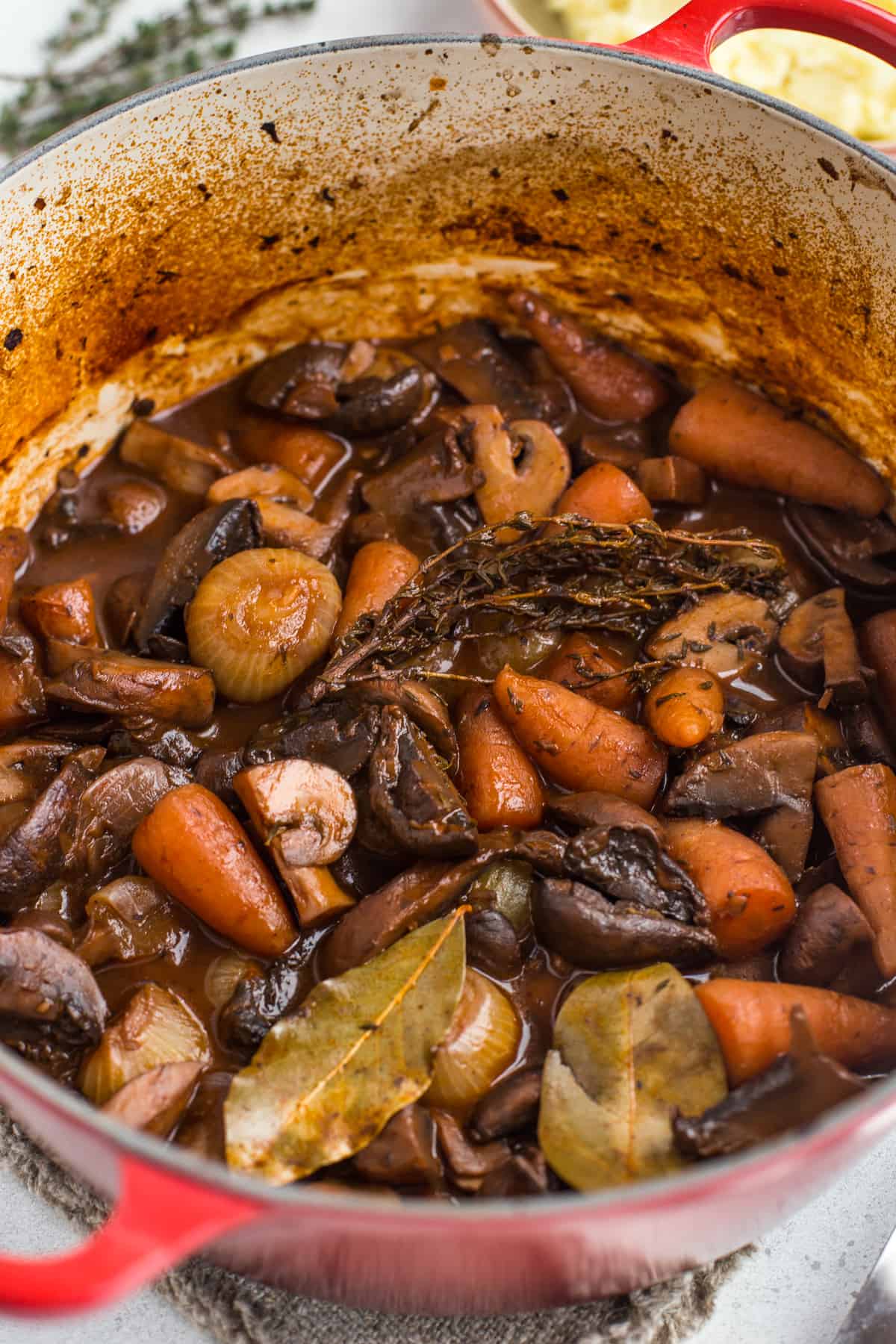 Vegetarian bourguignon in a casserole dish with carrots and onions.