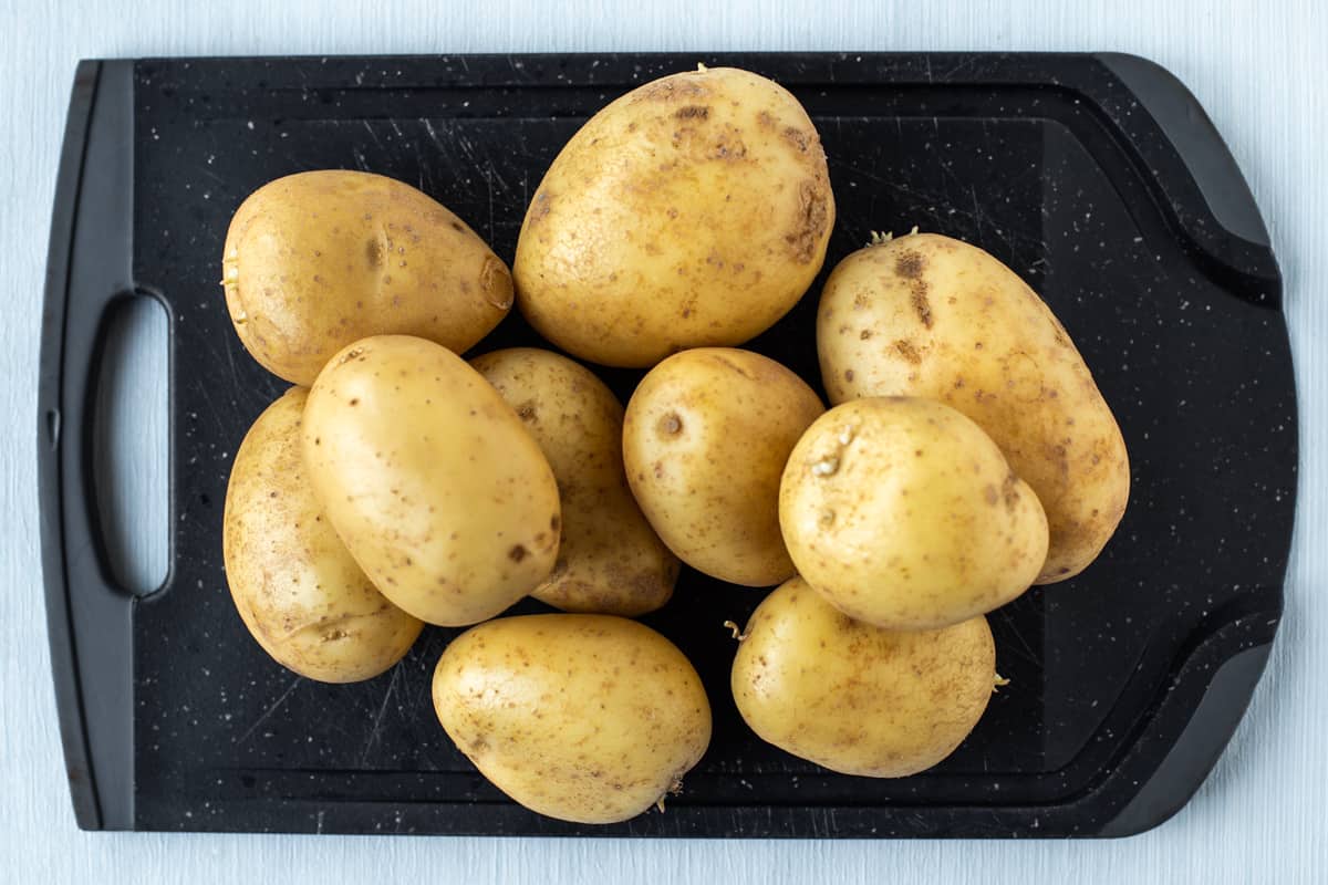 A pile of Maris Piper potatoes on a chopping board.