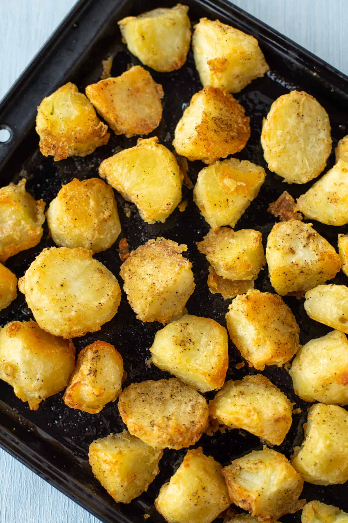 A baking tray full of crispy, golden brown roast potatoes.