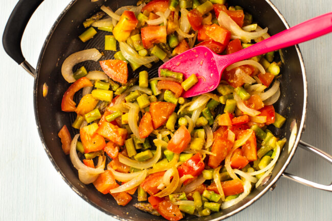 Vegetables being sautéed in a frying pan.