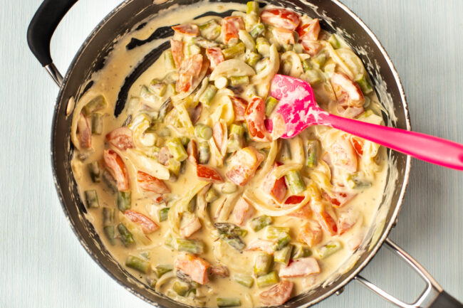 Vegetables in a creamy sauce in a frying pan.
