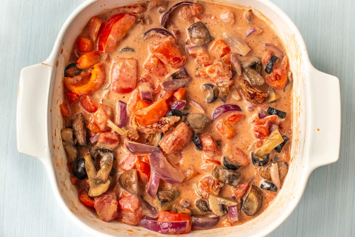 Roasted vegetables in a creamy tomato sauce in a dish.