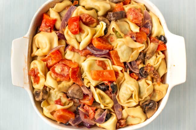 Tortellini mixed with roasted vegetables and creamy tomato sauce in a baking dish.