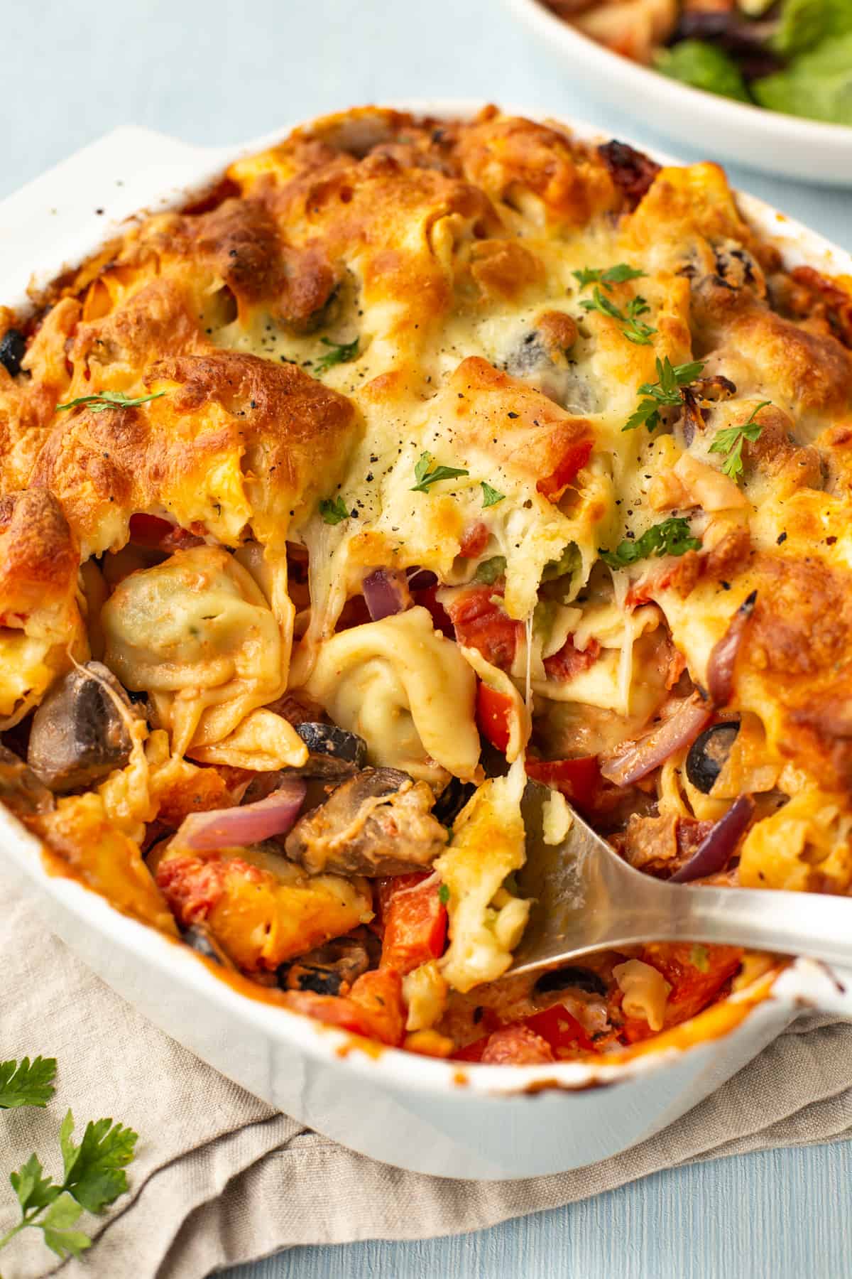 A cheesy vegetarian pasta bake in a dish with a scoop removed.