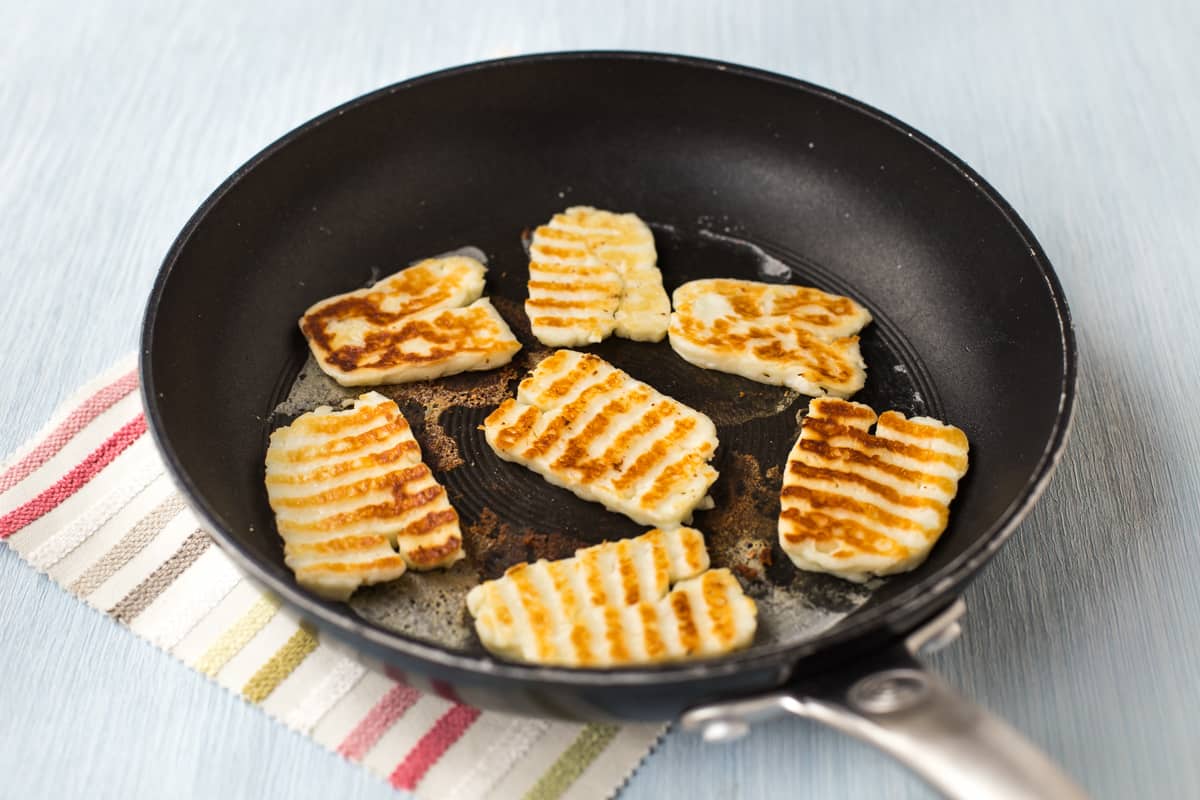Halloumi cheese with grill lines in a frying pan.