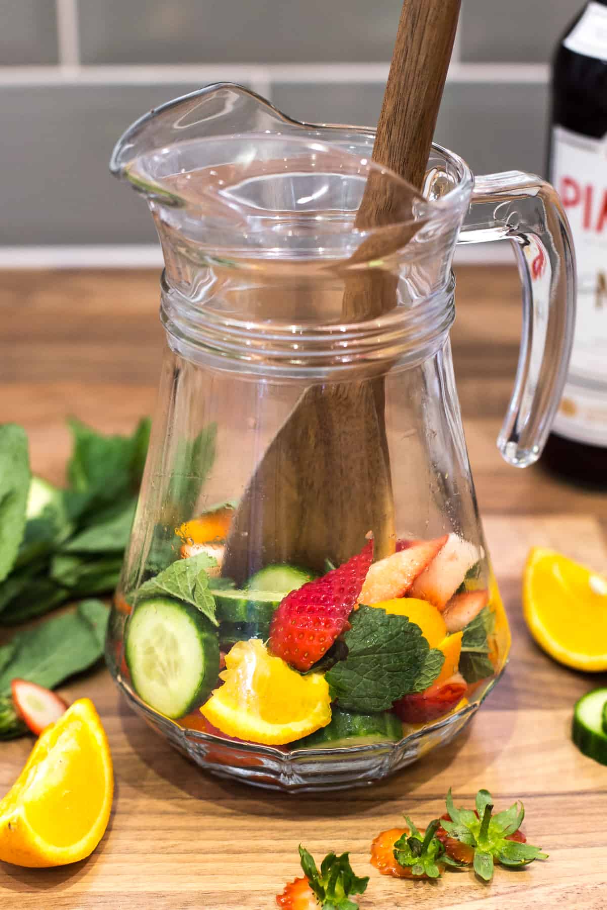 Cucumber, oranges and strawberries in a large glass jug.