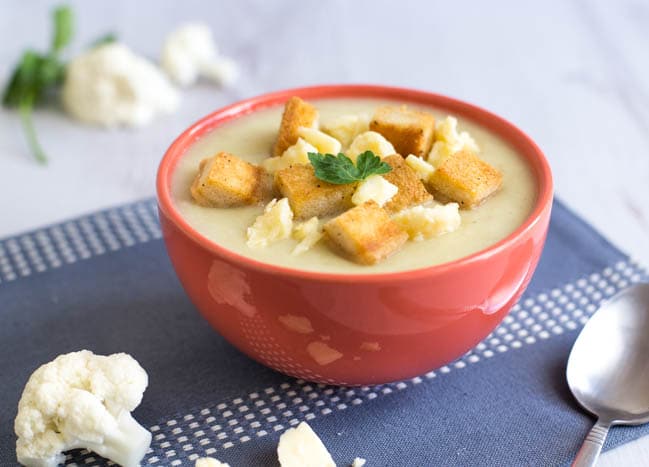 Bowlful of creamy cauliflower cheese soup with crispy croutons