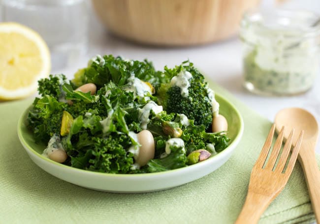 A plateful of kale salad topped with heaps of superfoods and a creamy dressing.