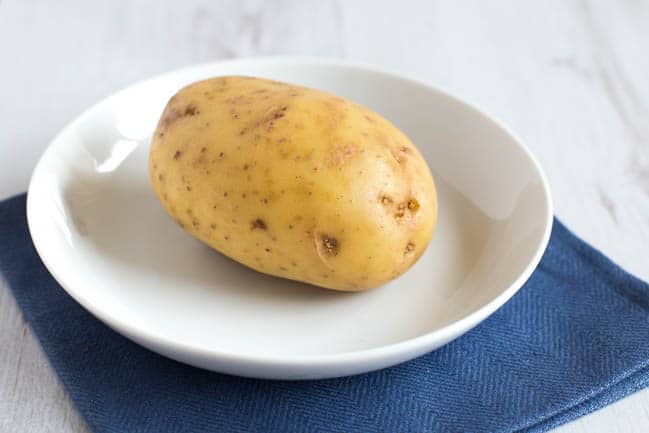 A raw potato on a plate.