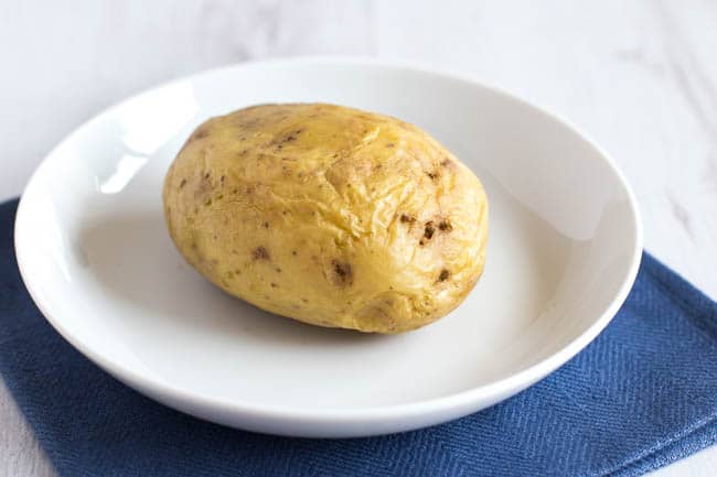 A part-cooked potato on a plate.