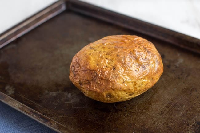 A crispy baked potato on a baking tray.