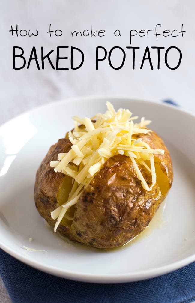 A crispy jacket potato on a plate, topped with melted butter and grated cheese.