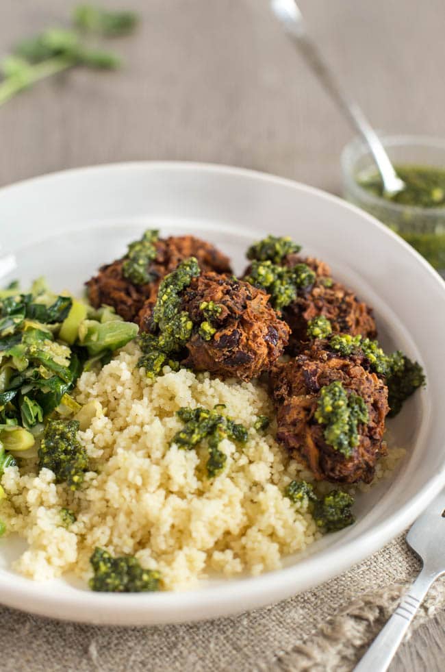A portion of vegan koftas with couscous and greens in a bowl.