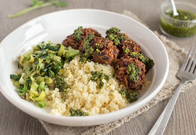 Vegetarian bean koftas in a bowl with couscous and greens.