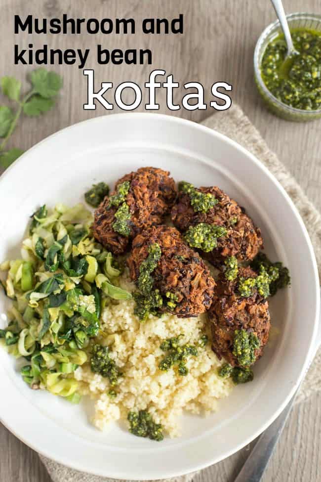 Kidney bean koftas in a bowl with couscous and sauteed greens, drizzled with pesto.