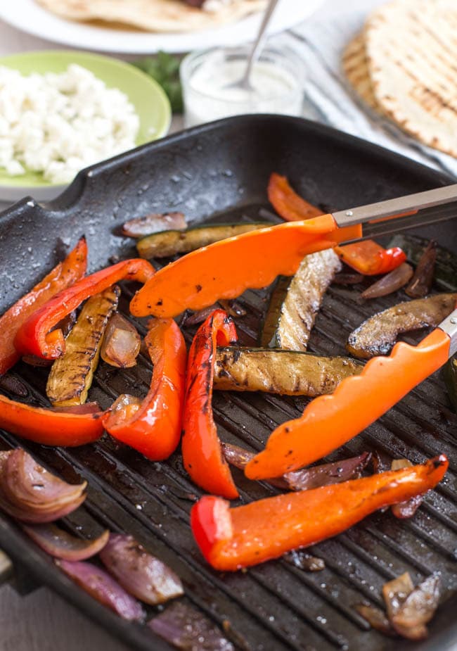 Mediterranean vegetables (peppers, courgette, red onion) cooking in a griddle pan.